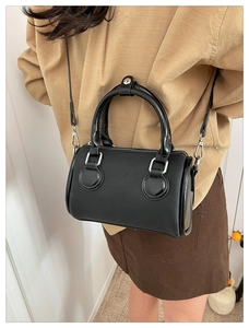 Detailed shot of black barrel bag with textured fabric, glossy leather and silver hardware