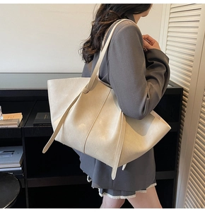 Detail of a large cream tote bag showing smooth faux leather texture and decorative straps