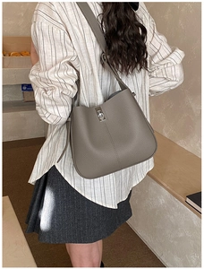 Detail of grey lychee leather bucket bag with silver metal swivel lock and wide strap