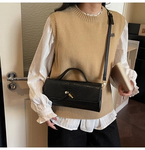 Détail d'un sac à main vintage en similicuir crocodile noir avec fermoir en métal doré