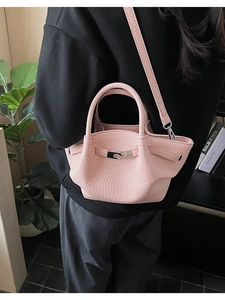 Detail of pink lychee textured bucket bag with wavy edge and silver metal twist lock