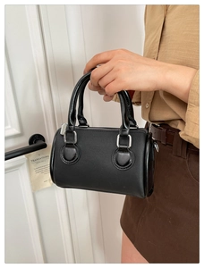 Macro shot of black cylindrical handbag with fine twill texture and silver hardware