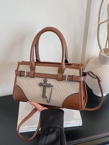 Retro two-tone leather handbag with woven texture and a cross charm on a dark surface