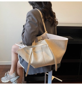 Detail of a large beige tote bag in soft leather shown on shoulder for daily commute