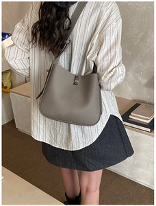 Detail of taupe litchi grain leather bucket bag featuring elegant metal twist lock closure