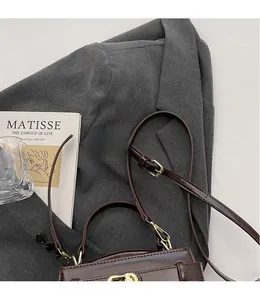Dettaglio della tracolla regolabile e della chiusura dorata su borsa marrone scuro