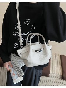 Detail of off-white lychee texture bucket bag with dual handles and metal lock buckle
