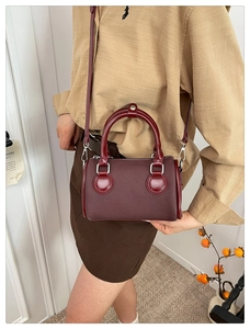 Detalle del mini bolso Boston burdeos en tela texturizada y asas de cuero fino