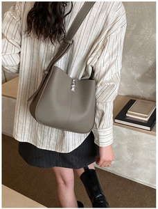 Detail of grey pebble leather bucket bag with silver metal swivel lock on adjustable strap