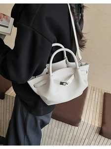 Detail of white litchi grain bucket bag with metal twist lock and leather texture