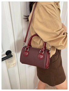 Detalle de bolso Boston granate con costuras finas y ganchos metálicos dorados