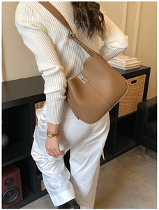 Brown lychee grain leather bucket bag with silver twist lock shown on a model shoulder