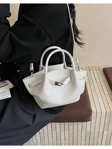 White lychee leather bucket bag with silver metal buckle worn by model in a side view