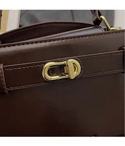 Dettaglio della chiusura in metallo dorato e cuciture su una borsa in pelle marrone