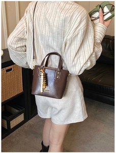 Gros plan d'un sac seau en similicuir marron avec breloque en bois et boucle dorée