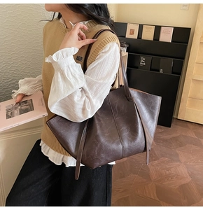 Detail of vintage large capacity brown tote bag with oily leather texture on model