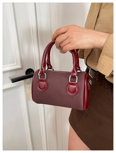 Close-up of wine red Boston bag showing twill fabric texture and shiny leather trim