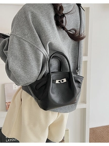 Detailed back view of a black lychee texture bucket bag with silver buckle on a model