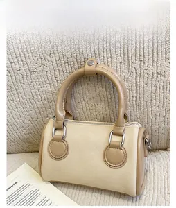 Detailed close-up of beige canvas Boston bag with brown leather trim on textured background
