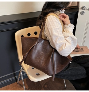 Detail of a large vintage brown PU leather tote bag featuring slim straps and drawstring accents