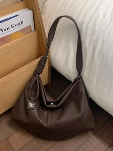 Retro dark brown leather tote bag with braided knot strap and vintage artistic background