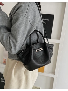 Detail of black pebbled leather handbag with silver twist lock and pleated side texture