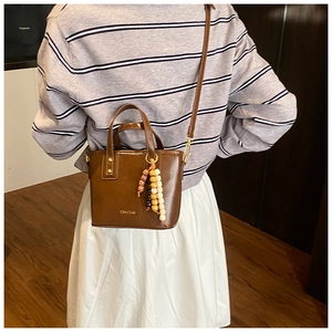 Gros plan d'un sac seau marron vintage avec breloque en perles et bandoulière réglable
