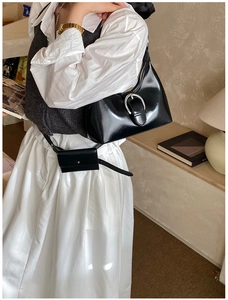 Détail du sac croissant noir brillant avec boucle argentée et mini pochette