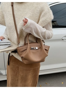 Detail of brown lychee grain leather mini bucket bag with silver turn-lock and model outfit