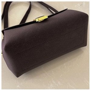 Detail of lychee pattern leather and gold twist lock on dark brown crossbody bag