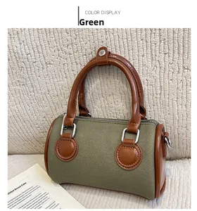 Detail of green canvas Boston bag with brown handles and silver metal hardware accents