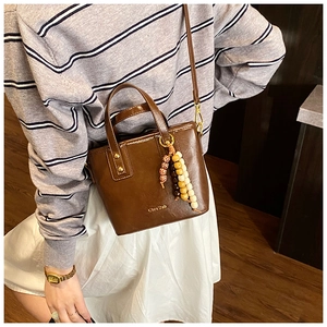 Détail du sac seau vintage marron foncé avec charme perlé coloré et garnitures métalliques
