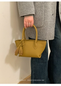 Lifestyle shot of olive yellow leather handbag with tassel detail and retro vibe