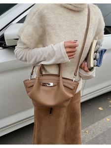 Detail of brown litchi leather bucket bag with silver metal clasp and crossbody strap