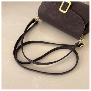 Macro shot of dark brown retro shoulder bag with cracked texture and gold buckle