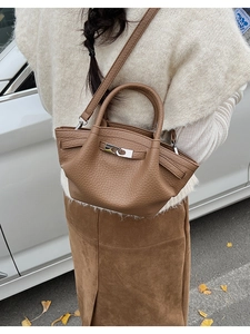 Detailed macro view of the brown litchi grain leather texture and silver metal twist lock