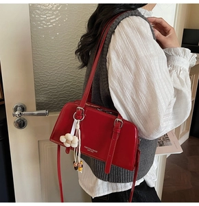 Detail of red leather tote bag featuring fashion text and floral charm on model