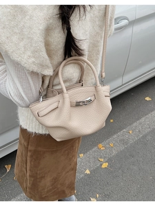 Street view of beige leather bucket bag with silver buckle and litchi texture on street
