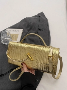 Sac à main doré texture serpent avec poignée supérieure et bandoulière sur une veste chic