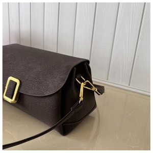 Close-up of textured brown leather handbag with elegant gold metal buckle and clasp