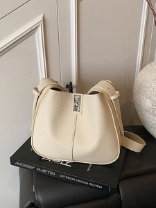 Minimalist beige pebble leather bucket bag with silver turn-lock and wide shoulder strap