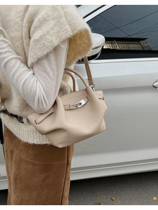 Detail view of the pebbled leather texture and metal buckle on the cream bucket bag