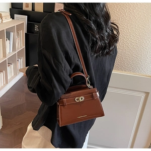 Dettaglio della borsa a tracolla in pelle marrone scuro con chiusura a scatto dorata