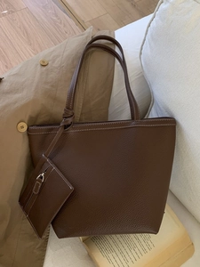 Large dark brown pebble leather tote bag with small zipper pouch in stylish setting