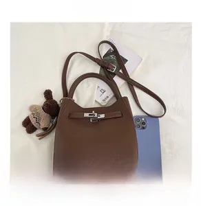 Vue détaillée du sac seau en cuir litchi marron avec fermoir argenté et bijou d'ours