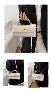 Detailed close-up of cream textured leather handbag with gold metal twist-lock buckle