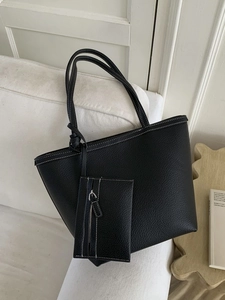 Black large capacity faux leather tote bag with white contrast stitching on a sofa