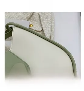 Macro shot of sage green and cream faux leather handbag with circular magnetic buckle
