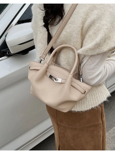Outdoor street shot of a beige leather bucket bag worn as a stylish crossbody bag