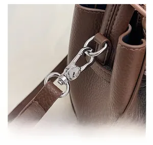 Gros plan du crochet en métal argenté et du cuir grainé marron sur le sac seau